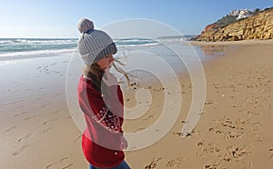 Girl in a bobble hat on the beach in Portugal in winter