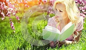 Girl with Book. Blonde Young Woman Lying on the Grass