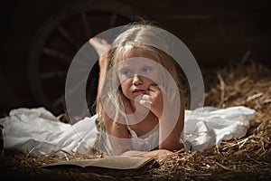 Girl with a book in the hay