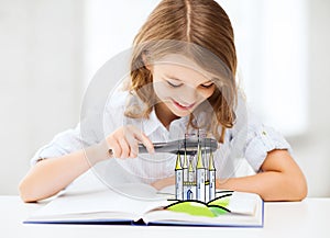 Girl with book looking to castle through magnifier