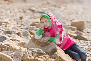 Girl bored at the seaside in offseason lay down on a big rock