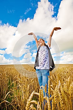 Girl with both arms up in sky standing in wheat field
