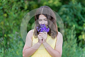 Girl with bouquet of blue wild flowers outside in summer