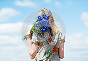 The girl with a bouquet of cornflowers on sky background.