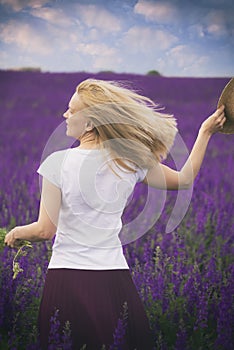 A girl with a bouquet of flowers in a lilac lushly field.