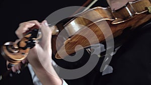 Girl bows over the strings of a violin. Black background. Close up