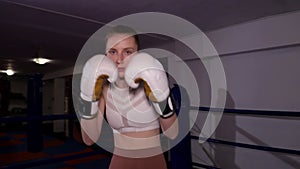 Girl boxer actively waving his fists in front of the camera, boxing training