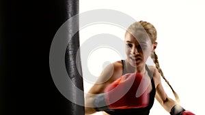 Girl boxer with passion beats his fist on punching bag