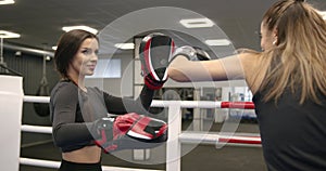 Girl boxing gloves with a female trainer on the arena