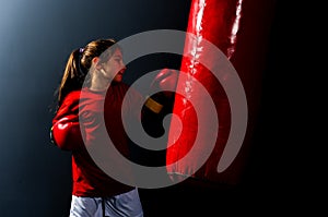 A girl in boxing gloves hits a punching bag