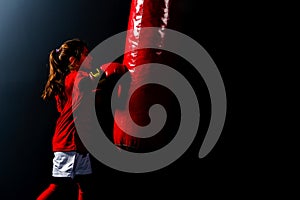 A girl in boxing gloves hits a punching bag photo