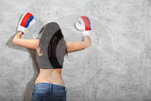 Girl in boxing gloves leaned to wall