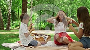 Girl and boy blowing bubbles in summer park. Smiling woman relaxing with kids