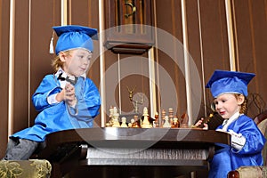 Girl and boy in blue suits play chess