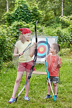 Girl and boy with bow near sport aim