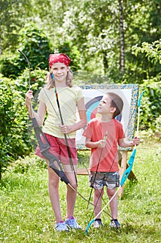 Girl and boy with bow near sport aim