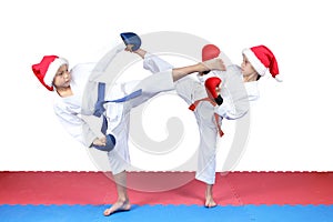 Girl and boy in caps of Santa Claus are beating kick leg