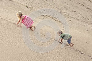 Girl and boy Climbing On The Sand dune. Summer day