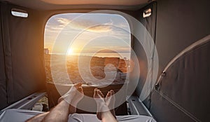 Girl boy couple sleeping in mini van and looking on the ocean at summer sunset scenery