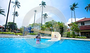 Girl and boy enjoying the slide by swimming pool