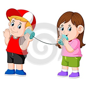Girl and boy experimenting talking on a wired tin cans phone