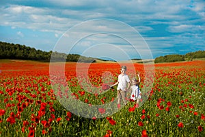 Girl and boy in a field of red poppies. concept of childhood, happiness, family