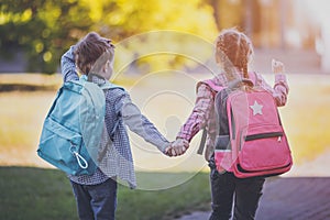 Girl and boy going to the school holding hands to study at it.