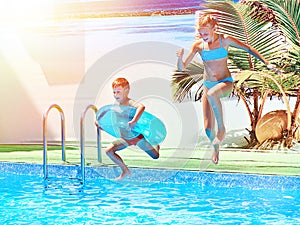 Girl and boy jumping into resort pool