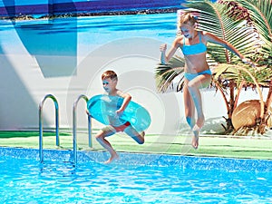 Girl and boy jumping into resort pool