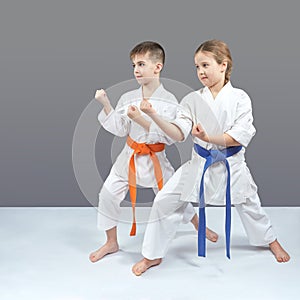 A girl and a boy in karategi stand in a karate rack