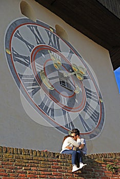 Girl and boy are kissing nearly city clock tower