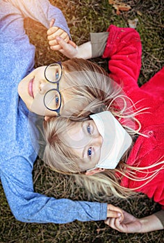 Girl and boy lie on the grass in a facial mask