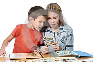 Girl and boy with magnifier looking his stamp collection isolate