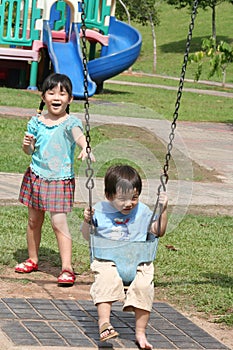 Girl & boy at the park swinging