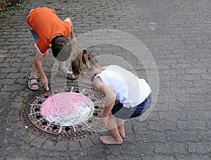 Girl and boy playing outside, paints  on the street