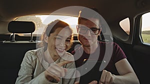 Girl, boy and road trip to the beach. Couple of young adult friends sitting in car at sunset, smiling and taking selfie