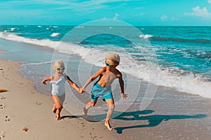 Girl and boy running at beach, kids play with waves