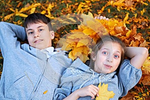 Girl and boy teenager having holiday in autumn city park, lying on grass, posing, smiling, playing and having fun. Bright yellow