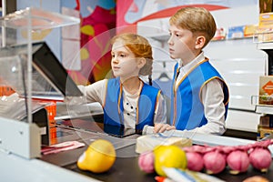 Girl and boy in uniform at the register, sellers