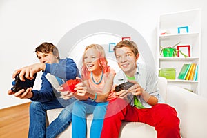 Girl and boys with joysticks playing game console