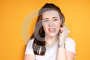 Girl in braces clenches her hand into a fist and frowns irritably with pain clenching her teeth