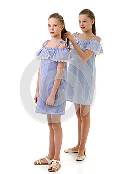 Twin Sisters in Identical Light Dresses, Girl Braiding her Siste photo