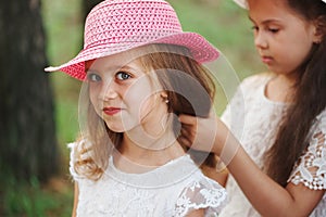 Girl braids her friend`s braid in park