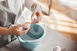 Girl breaks an egg into a bowl for baking. culinary cover