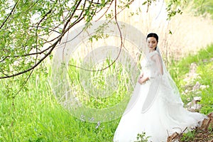 Girl bride in wedding dress with elegant hairstyle, with white wedding dress Standingin the grass by the river