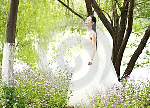 Girl bride in wedding dress with elegant hairstyle, with white wedding dress Standingin the grass by the river