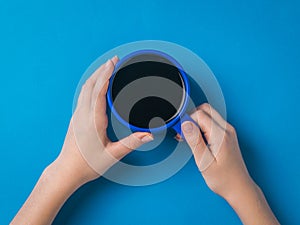 A girl with a bright blue coffee mug in her hands on a blue background