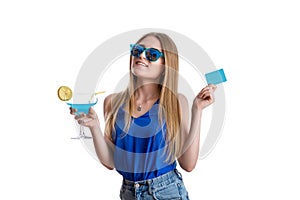 A girl in bright blue jeans and a blouse with a blue cocktail with lemon and a credit card