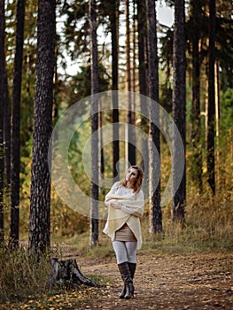 Girl in bright clothes against a background of tree trunks in the autumn forest