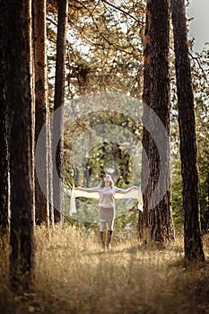 Girl in bright clothes against a background of tree trunks in the autumn forest